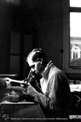 Fotoalbum tillägnat Professor Torsten Hellman från histologkursen 1929.
Fotoalbum tillägnat Professor Torsten Hellman med tacksamhet och vördnad från histologkursen 1929. Bildtext "Ask". Mannen vid mikroskopet har vänstra handen i bandage. Ett fönster i östra fasaden på dåvarande fysiologiska institutionen ses utanför fönstret.
- Olof Ask (1909-1988) disputerade i Uppsala 1941 på en avhandling om spina bifida. Från 1956 var han överläkare med ansvar för den medicinska vården på St Lars sjukhus i Lund
Nyckelord: Histologiska avdelningen;Anatomiska Institutionen;Mikroskop;Mikroskopist;Medicinska fakulteten i Lund;Locus Medicus Lundensis