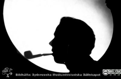 1928 års kurs i histologi i Lund
Fotoalbum märkt Histologikursen anno 1928. 
Detta album innehåller bilder från dåvarande histologiska avdelningen på anatomiska institutionen i Lund på Biskopsgatan 7. Liksom de övriga i serien skapades det av kursdeltagarna och tillägnades kursledaren professor Torsten Hellman som uppskattning av hans lärargärning. Bildtext  "Göran Gerner.". Siluett mot mikroskopprojektorns runda skiva utan preparat i den.
Bildkälla Stiftelsen Locus Medicus Lundensis 250317.
Nyckelord: Locus Medicus Lundensis;Medicinska fakulteten i Lund;Histologiska avdelningen;Sydsvenska Medicinhistoriska Sällskapet;SMHS;Anatomiska Institutionen;Studenter;Lärare
