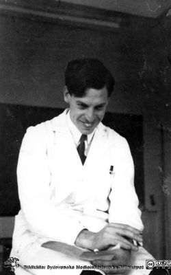 Bild i fotoalbum  tillägnat professor Torsten Hellman från deltagarna i histologikursen ht 1930. 
Fotoalbum  "TILL PROFESSOR TORSTEN hELLMAN MED TACK FRÅN DELTAGARNA I HISTOLOGIKURSEN HÖSTTERMINEN 1930".  Bildtext "MOBERG håller förhör. Vad skall jag nu fråga om? Svaret tycks bli roligt! Ja nästan mer än så! Men i alla fall var det rätt".  Bildkälla stifteleen Locus Medicus Lundensis och Sydsvenska Medicinhistoriska Sällskapet / SMHS. Fotograf okänd.
Nyckelord: Histologiska avdelningen;Anatomiska Institutionen;Entrétrappa;Medicinska fakulteten i Lund;Sydsvenska Medicinhistoriska Sällskapet;Locus Medicus Lundensis;Lärare;Elever;Förhör