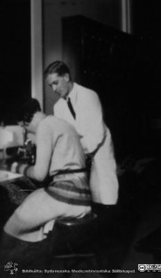 Bild i fotoalbum  tillägnat professor Torsten Hellman från deltagarna i histologikursen ht 1930. 
Fotoalbum  "TILL PROFESSOR TORSTEN hELLMAN MED TACK FRÅN DELTAGARNA I HISTOLOGIKURSEN HÖSTTERMINEN 1930".  Bildtext "Undervisning, den lille". Kanske den mest kortvuxne av kursamanuenserna, här vid en kvinnlig student. 
Bildkälla stifteleen Locus Medicus Lundensis och Sydsvenska Medicinhistoriska Sällskapet / SMHS. Fotograf okänd.
Nyckelord: Histologiska avdelningen;Anatomiska Institutionen;Entrétrappa;Medicinska fakulteten i Lund;Sydsvenska Medicinhistoriska Sällskapet;Locus Medicus Lundensis;Lärare