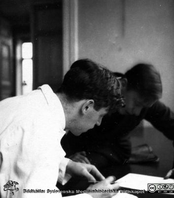 Fotoalbum tillägnat professor Torsten Hellman från histologikursen HT 1930
Fotoalbum  "TILL PROFESSOR TORSTEN HELLMAN MED TACK FRÅN DELTAGARNA I HISTOLOGIKURSEN HÖSTTERMINEN 1930".  Bildtext "Moppe diskuterar tennis.". Moppe är kanske amanuensen Moberg. Foto kanske i histologiska avdelningens kurslaboratorium.
Bildkälla stiftelsen Locus Medicus Lundensis och Sydsvenska Medicinhistoriska Sällskapet / SMHS. Fotograf okänd.
Nyckelord: Histologiska avdelningen;Anatomiska Institutionen;Medicinska fakulteten i Lund;Sydsvenska Medicinhistoriska Sällskapet;SMHS;Locus Medicus Lundensis;Elever;Lärare