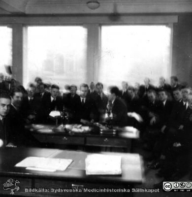 Fotoalbum tillägnat professor Torsten Hellman från histologikursen HT 1930
Fotoalbum  "TILL PROFESSOR TORSTEN HELLMAN MED TACK FRÅN DELTAGARNA I HISTOLOGIKURSEN HÖSTTERMINEN 1930".  Bildtext "Den månghövdade skaran.".  Foto med skakig kamera, kanske i histologiska avdelningens kurslaboratorium.
Bildkälla stiftelsen Locus Medicus Lundensis och Sydsvenska Medicinhistoriska Sällskapet / SMHS. Fotograf okänd.
Nyckelord: Histologiska avdelningen;Anatomiska Institutionen;Medicinska fakulteten i Lund;Sydsvenska Medicinhistoriska Sällskapet;SMHS;Locus Medicus Lundensis;Elever