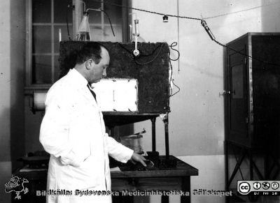 Fotoalbum  från histologkursen 1931.  Bildtext "G. Glimstedt".  Amanuensa Gösta Glimstedt (1905 - 1970), från c:a 1943 efterträdare till Torsten Hellman.  Foto troligen i kurslaboratoriet vid okänd apparat (värmeskåp?)
Bildkälla Stiftelsen Locus Medicus Lundensis 250317. Sydsvenska Medicinhistoriska Sällskapet / SMHS. Fotograf okänd.
Nyckelord: Amanuens;Medicinska fakulteten i Lund;Anatomiska Institutionen;Histologiska avdelningen