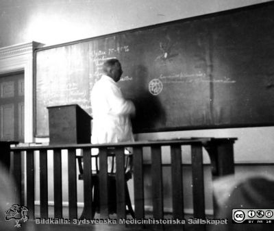 Fotoalbum från histologikursen 1931
Fotoalbum från histologikursen 1931. Bildtext "'Farbror' ritar och berättar". Professor Torsteh Hellman vid svarta tavlan i stora föreläsningssalen. 
Bildkälla Stiftelsen Locus Medicus Lundensis 250317. Sydsvenska Medicinhistoriska Sällskapet / SMHS. Fotograf okänd.
Nyckelord: Universitetet i Lund;Histologiska avdelningen;Anatomiska Institutionen;Föreläsning;Locus Medicus Lundensis;Medicinska fakulteten i Lund;Universitetet i Lund