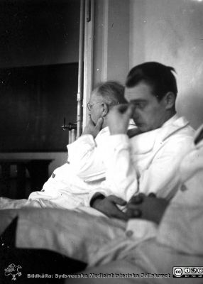Fotoalbum  från histologkursen 1931.  Bildtext "Ombytta roller". Professor Torsten Hellman och en amanuens som åhörare till en föreläsning av amanuens Gösta Glimsted (fil imgLA2250318ff367). En annan amanuens är mest utanför bilden.
Bildkälla Stiftelsen Locus Medicus Lundensis 250317. Sydsvenska Medicinhistoriska Sällskapet / SMHS. Fotograf okänd.
Nyckelord: Medicine studerande;Histologiska avdelningen;Anatomiska Institutionen;Medicinska fakulteten i Lund;Locus Medicus Lundensis;Universitetet i Lund