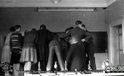 Fotoalbum tillägnat Professor Torsten Hellman med tacksamhet och vördnad från histologkursen 1929. Albumtext "Slutet gott - allting gott. Fixeringsbild. Var är chefen?" När detta skrivs nästan ett sekel senare kan man kanske gissa att albumtexten skall tolkas som att bilden visar en variant av stående ovation för chefen Torsten Hellman.
Bildkälla Locus Medicus Lundensis 250317 och Sydsvenska Mediinhistoriska Sällskapet / SMHS. Fotograf okänd.
Nyckelord: Histologiska avdelningen;Anatomiska Institutionen;Medicine studerande;Medicinska fakulteten i Lund;Locus Medicus Lundensis;Sydsvenska Medicinhistoriska Sällskapet