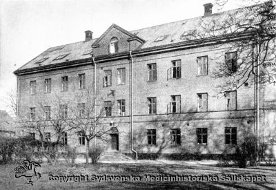 Första lasarettsbyggnaden i Lund, byggd för sitt ändamål, sedd från sydost
Lasarettsbyggnaden från 1848-1850, från 1868 medicinsk klinik, från 1918 och till 1960-talet lungklinik. Därefter olika institutioner inom humanistiska fakulten vid Lunds Universitet. Nedersta våningen var från 1918 och till dess jubileumskliniken uppfördes på norra området radiologisk sjukavdelning. Byggnaden var från början reveterad. På Beijers rining motsvaras den av den västra flygeln. Vindsgluggarna blev först 1925 ersatta med mansardfösterkupor. 
Från Borelius 1918.
Nyckelord: Lasarett;Lund;Universitetssjukhus;Universitet;1850;Medicin;Radiologi;Lunga;Lungklinik;Universitet;Lindgren;Borelius;1918