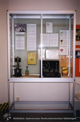 Medicinhistoriska museet i Lund. Röntgenutställning på 1990-talet: avarter
Foto av en monter som visar olika avarter av användning av joniserande strålning: radium / radonberikat vatten eller andningsluft från en speciell apparat (ett emanatorium), en flaska med radiumberikat bordsvatten, reklam för en hälsokälla som sades ha radioaktivt vatten (dess vatten var och är utmärkt, men inte särskilt radioaktivt), tvättmedel med namn som anspelar på strålning etc.
Röntgenutställningen, Medicinhistoriska Museet i Lund. Foto på 1990-talet. 
Nyckelord: Medicinhistoriskt;Museum;Lund;Utställning;Röntgen;Radiologi