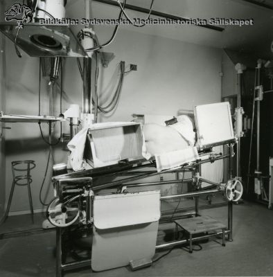 Röntgenundersökning i Lund av patient i sidoläge, med ryggen blottad, i mitten på 1900-talet.
 Kanske på röntgen II i Lund.
Nyckelord: Röntgen;Kapsel 11;Undersökning;Diagnostik;Lund;Radiologi