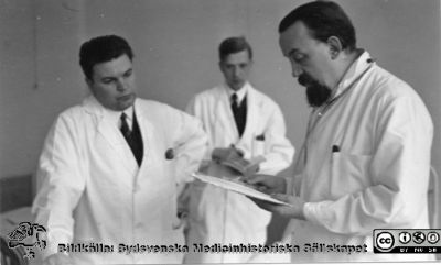 Läkarrond på medicinska kliniken i Lund på 1930-talet
Professor Erik Ask-Upmark (1901 - 1985; längst till höger i bilden) går rond på medicinska kliniken i Lund. Han var utbildad i Lund och blev professor i internmedicin i Uppsala 1946 där han också pensionerades 1968. Läkaren längst till vänster i bild är Bertil Scherstén. I bakgrunden kanske Olof Nordenfelt, mycket osäkert.  Foto i mitten på 1930-talet av sjuksköterskan Elsa Arnberg född Thomaeus (1915-1995). Bildkälla hennes svärson Henry Svensson 2014. 
Nyckelord: Lund; Universitet; Professor; Medicin; Internmedicin;