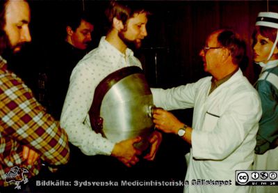 Respiratortekniker Ragnar Magnusson visar hur en s.k. kyrassrespirator skall sitta på patientens bål.
Från en utställning om respiratorvård vid 100-årsjubileet för infektionskliniken i Malmö 1980. Utställningen stod i anslutning till sjukhusets personalmatsal. Respiratortekniker Ragnar Magnusson visadr hur en s.k. kyrassrespirator skall sitta mot patientens bål. Bildkälla Klas Ramnerö 2014.
Nyckelord: UMAS;MAS;Malmö_;Allmänna;Sjukhus;Infektionsklinik;Respirator;Utställning;Jubileum