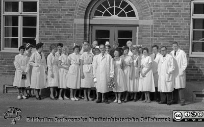 Avtackning av Albert Flaum på epidemisjukhuset 1961
Alfred Flaum (1895-1982) 1961 på dåvarande epidemisjukhuset, rimligen vid hans pensionering. Alfred Flaum ses i centrum med blommor i handen. Från längst till höger: Jerker Nermark, Karl Emil Thulin och Bo Ursing. I bakersta ledet i mitten ses Bengt Rosbergs hår, högra öra och panna. Bredvid honom Erik Dahlqvist med en sköterskemössa delvis skymmande vänster hakdel och mungipa. Bland alla kvinnorna återfinns arbetsterapeut Ingrid Wallerström, sekreterarna Tyra Ahlström och Gun Mårtensson samt sköterskorna Ann-Marie Karlson och Anna-Lisa Weingardt. Samma fototillfälle som SMHS5787. Foto utanför en av epidemisjukhusets paviljonger. Jfr bild SMHS13699 och 13700. Från negativ. 
Nyckelord: Lasarett;Lund;Universitet;Universitetssjukhus;USiL;Epidemi;Infektion;Klinik;Pensionering