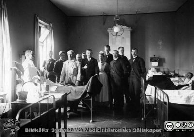 Professor Seved Ribbing går rond
Bilderbok 7b, 1908 i AF:s arkiv. Rond med prof. Seved Ribbing på gamla Medicinen. Från vänster: underläkare Bergkvist, Sjöbring, Westergård, Seved Ribbing, Gråberg, Hirschlaff, Cavallin, Syster Inez Olsson, Wallengren, Alling, Virde och G. Pallin. 
Syster Inez var den sista Sophiasystern, som tjänstgjorde vid lasarettet.
Bild SMHS2573_000_01 i bildsamlingen på Regionarkivet kommer från samma negativ och sägs där vara från år 1900.
Nyckelord: Arkiv;Akademiska;Föreningen;Tusses arkiv