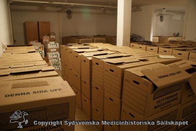 Del av Medicinhistoriska Museets boksamling i förråd i Eslöv 2010
Medicinhistoriska museet i Lunds boksamling hade vid stängningen packats i ett stort antal boklådor. De värdefullaste gick till Universitetsbiblioteket i Lund. De mindre värdefulla (c:a 900 lådor) hade lagrats i ett gammalt skyddsrum på vårdcentralen Tåbelund i Eslöv. Samlingen gallrades våren 2010 av Gunnar Broberg, Håkan Westling, Bengt Lindskog, Anders Biörklund och Berndt Ehinger. Kvar blev c:a 200 boklådor som skickades till ett kommersiellt lager i Lund eftersom lokalen i Tåbelund skulle byggas om. Bilden visar ett par hundra av de 900 boklådor som förvarades i Tåbelund.
Nyckelord: Medicinhistoriskt;Museum;Anders;Biörklund;Boksamling,Gallring,Tåbelund;Håkan;Westling;Gunnar;Broberg;Bengt;Lindskog;Eslöv;Berndt;Ehinger