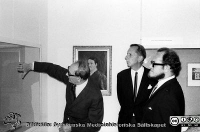 Från den medicinhistoriska utställningen "Vårda - bota" på Kulturen i Lund i september - oktober 1968, 
Medicinhistorisk utställning "Vårda - bota" på Kulturen i Lund i september - oktober 1968, ordnad med anledning av lasarettets 200-årsjubileum. Omärkt bild. Albert Flaum demonstrerar något för gynekologen, docent Lennart Ploman och Alf Wallerström (med skägg). Porträtt av barnmorskan, "jungfru Christin" på väggen. Originalfoto av Matts Bergmark 17/10 1968. I pärm MS 5-574.
Nyckelord: Kulturen;Lund;Medicin;Historia;Jubileum;Universitetssjukhus;Universitetsklinik;Utställning