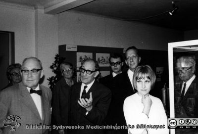 Från den medicinhistoriska utställningen "Vårda - bota" på Kulturen i Lund i september - oktober 1968, 
Medicinhistorisk utställning "Vårda - bota" på Kulturen i Lund i september - oktober 1968, ordnad med anledning av lasarettets 200-årsjubileum. Omärkt bild. Till vänster Ebbe Cronberg (privatpraktiserande läkare i Malmö). Alfred Flaum i bildens mitt gestikulerande. Gynekologen Lennart Ploman som nr 3 från höger (den längste i sällskapet) och Sölve Welin längst till höger, genom monterns glasrutor. Kulturens Margareta Alin i ljus jumper. Originalfoto, fotograf Matts Bergmark. Bild i pärm MS 5-574.
Nyckelord: Kulturen;Lund;Medicin;Historia;Jubileum;Universitetssjukhus;Universitetsklinik;Utställning