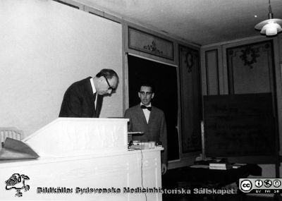 Sydsvenska Medicinhistoriska Sällskapets höstmöte 17/10 1968
 Mötet hölls i anslutning til den medicinhistorisk utställningen, "Vårda - bota", på Kulturen i Lund i september - oktober 1968, ordnad med anledning av lasarettets 200-årsjubileum. Ordförande Alfred Flaum justerar protokollet som just lästs upp av sekreterzren Bengt Lindskog. Foto av Matts Bergmark i pärm MS 5.574.
Nyckelord: Lasarettet;Lund;Universitetssjukhuset;USiL;Utställning;rsmöte;Kulturen