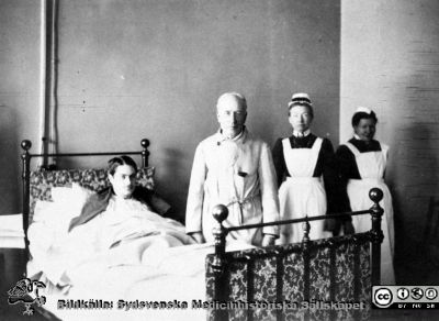 Prof Seved Ribbing går rond på gamla medicinska kliniken 
Från samma negativ som bild SMHS6246_000_01.
Foto nära år 1900, troligen ett enskilt sjukrum (s.k. privatrum) eftersom sängen är lite mer påkostad än de på flerbäddssalarna. 
Sophiasystern bör vara syster Inez. Fotot är frimligen taget av  Lina Jonns Eftr., Lund (Per Bagge).
Nyckelord: Universitet;Sjukhus;Lasarett;Lund;Medicin;Klinik