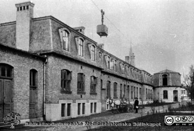 Ekonomibyggnaden från 1904 vid Lasarettet i Lund
Märk mattransportvagnen på linbanan. Vid lasarettets häst och vagn för transporter står syssloman P. Lundborg. Publicerad i Flaum (1968) sid. 193.
Nyckelord: Lasarett;Lund;Ekonomi;Tvätt;Transport;Administration;Infrastruktur;Verkstad;Kök