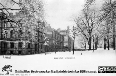 Fotografiskt vykort med 1867/68 års kirurgiska klinik i Lund från sydost, i vinterväder
Foto Lina Jonn 1901 (Per Bagge). Från 35 mm repronegativ i lasarettsfotografernas pärm "Gammalt A". Lund.
Nyckelord: Lund;Lasarett;Kirurgi;Klinik;Exteriör;Vykort;Universitet;Universitetssjukhus