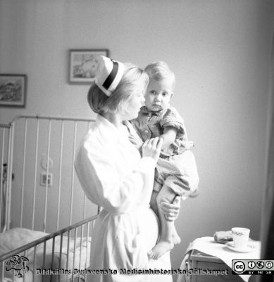 SSSH-sköterska med barn nära 1970
Pärm "Div. tagningar, 1960 och t.v.". SSSH-sköterska med barn. Foto på 1960-talet på barnkliniken i Lund. Se också bildfilerna 101108-011 (samma bild) och 101108-012 från samma fototillfälle och kanske bättre.
Nyckelord: Lund;Lasarettet;Universitet;Universitetssjukhus;Barn;Sköterska;Barnklinik;Omvårdnad