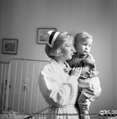 SSSH-sköterska med barn nära 1970
Pärm "Div. tagningar, 1960 och t.v.". SSSH-sköterska med barn. Foto på 1960-talet på barnkliniken i Lund. Se också bildfilerna 101108-011 (samma bild) och 101108-012 från samma fototillfälle och kanske bättre.
Nyckelord: Lund;Lasarettet;Universitet;Universitetssjukhus;Barn;Sköterska;Barnklinik;Omvårdnad