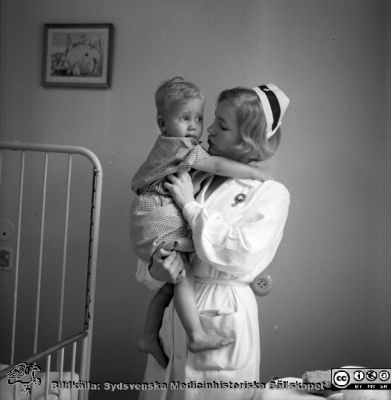 SSSH-sköterska med barn nära 1970
Pärm "Div. tagningar, 1960 och t.v.". SSSH-sköterska med barn. Foto på 1960-talet på barnkliniken i Lund. Se också bildfilerna 101108-011 och 101108-012 (samma bild) från samma fototillfälle och kanske bättre.
Nyckelord: Lund;Lasarettet;Universitet;Universitetssjukhus;Barn;Sköterska;Barnklinik;Omvårdnad