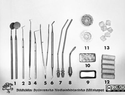 Tandläkarinstrument uppdukade 1969
Pärm "USiL div. tagningar. 1960 och t.v." Centraltandpol. 22/10, 1969. Tandl. Dahl, instrumentdukn. Från negativ. 
1. Speglar 2 st
2. Sond rak
3. Sond böjd
4. Sond märk
5. Pincett tand
6. Planinstrument
7. Sugrör 3 o 4 mm
8. Spets till Lic komb.-spruta
9. Borrkopp
10. Pellettsbehållare
11. Dappenglas
12. Cellstoffrullar
13. Tork sm
Nyckelord: Lund;Lasarett;Universitetssjukhus;Universitet;Dental;Tandläkare;Oral;Kirurgi