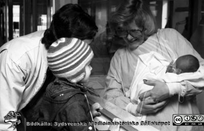 Kanske en barnmorska som visar upp ett nyfött barn för lillebror med pappa utanför fönstret.
Lasarettet i Lund. Pärm "USiL svart/vitt 1977". Foto för vårdskolan. Kanske en barnmorska som visar upp ett nyfött barn för lillebror med pappa utanför fönstret.
Nyckelord: Lund;Lasarett;Universitet;Universitetssjukhus;Lund;Obstetrik;BB;Nyfödd;Baby
