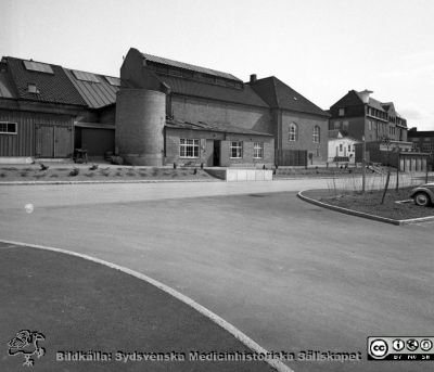 Lasarettet i Lund 1967. F.d. panncentralen
Lasarettsfotograferna i Lund. Pärm "Div. tagningar, 1960 och t.v.". Foto år 1967. Omärkt bild. Gamla panncentralen från 1918, verkstäder och medicinsk teknik när bilden togs. Det runda korta tornet är gamla skorstenens bas från 1918. Hela byggnaden ersattes 2014 av nytt strålbehandlingshus. 1918 års medicinklinik i fonden. Den ljusa baracken alldeles hitom medicinkliniken rymde rehabiliteringsavdelningen och den ortopedtekniska verkstaden. Den brandskadades i slutet av 1900-talet och revs. Från negativ.
Nyckelord: Lasarett;Lund;Universitet;Universitetssjukhus;USiL;Verkstäder;MTA;Medicinsk;Teknik;Avdelning