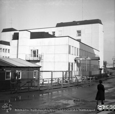 Laboratorieblockets första del på Lasarettet i Lund 1967
Pärm "Div. tagningar 1960 och t.v.". Omärkt bild. Foto 1967. Eb- och Ed-blocken byggdes först i det stora centralblockskomplexet. Eb-blocket ligger längst bort. Hitom ligger Ec- och Ed-blocken. Båda är lägre. Ea-blocket är ännu inte byggt. E-blocken byggdes för laboratorier och verkstäder. De experimentella låg i Ed-blocket. Verkstäderna låg i Ec-blocket. Sköterskan nere i bildens högra hörn bär vinteruniform. Från negativ.
Nyckelord: Lund;Lasarett;Universitet;Universitetssjukhus;USiL;Laboratorium;Lokaler;Verkstäder