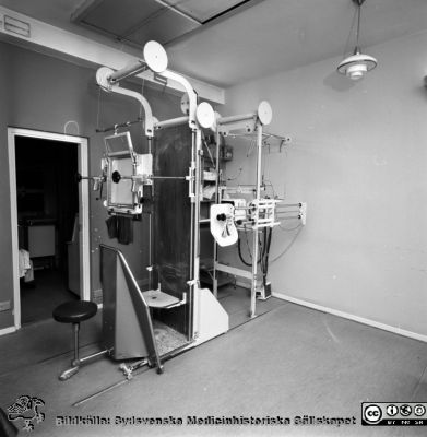 Stativ för genomlysning och undersökning med röntgenstrålar av fr.a. lungor vid Lasarettet i Lund, ett s.k. Forssellstativ.
Pärm "Div. tagningar 1960 och t.v."- Omärkt bild.  Foto 1967. Från negativ.
Nyckelord: Lund;Lasarett;Universitetssjukhus;Universitet;USiL;Rtg;Röntgen;Undersökning;Genomlysning;X-ray