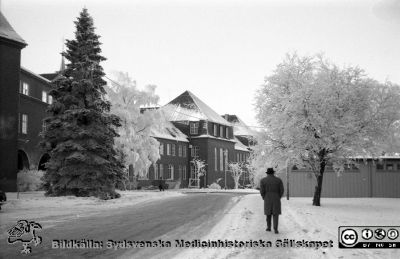 En rimfrostdag på Lasarettet i Lund 1961
Lasarettsfotograferna. Lund. Pärm "Div. tagningar, 1960 och t.v.". Lasarettets exteriörer. Vy mot lasarettskioskens baksida, valvet och medicinska kliniken en rimfrostdag 1961.  Från negativ.
Nyckelord: Lasarett;Lund;Universitet;Universitetssjukhus;USiL;Medicin;Klinik;Kiosk;Valv;Rimfrost;Reumatologi;Vinter