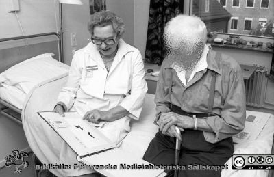 Sjukhusbibliotekarie och bibliotekschef Brita Arborelius med patient. 
Sjukhusfotograferna i Lund Pärm. Negativ, S/V. 1976. 153. Från negativ
Nyckelord: Lasarett;Lund;Universitet;Universitetssjukhus;USiL;Bibliotekarie;Sjukhus;Bok
