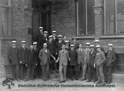 En patologkurs i Lund med professorn i patologi, John Forssman
Troligast kursfoto från en patologkurs i Lund. Professorn i patologi, John Forssman, vid ledstången, barhuvad och tunnhårig. Foto troligast på patologiska institutionens gårdstrappa under 1900-talets första halva av Lina Jonns Eftr, Lund (dvs Per Bagge). Monterat.
- 
Nyckelord: Patologi;Kursfoto;Kapsel 12