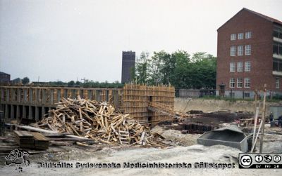 Laboratorieblocket (E) har börjat byggas i det blivande centralblocket
Pärm Lasarettsfoto, interiörer och exteriörer m.m. 1958-1960. Foto 1960. Längst till vänster ett hörn av den nya patologiska institutionen. Gamla vattentornet i bakgrunden. Dåvarande psykiatriska kliniken till höger. Från negativ
Nyckelord: Lasarett;Lund;Universitet;Universitetssjukhus;USiL;Psykiatrisk;Patologisk;Klinik;Bygge