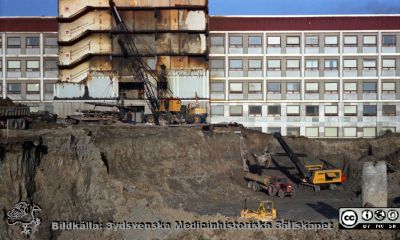 Centralblocket har börjat byggas
Pärm Lasarettsfoto, interiörer och exteriörer m.m. 1958 - 1960. Gropen grävs för C-blocket. Fasaden på AB-blockets trapphus har rivits, och där skall C-blocket ansluta. Foto 1960. Från negativ. 
Nyckelord: Lund;Lasarett;Universitet;Universitetssjukhus;USiL;Blocket;Bygge