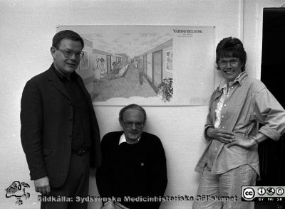 Projektledningen för projektet Vårdavdelning 2000 år 1987
Sjukhusfotograferna i Lund. Pärm Negativ, Dia, 1987. 72/1987. Foto vid en skiss av Vårdavdelning 2000. Från vänster Leif Granath (då chef för Näradministration lasarett), Claes Fredin (inredningsarkitekt på arkitektfirman SAMARK och medverkade i detta projekt) och längst till höger Elwy Ekman (projektledare; tidigare hygiensköterska på USiL och sedermera chef för centralförrådet). Från negativ. 
Nyckelord: Lasarettet;Lund;Universitetssjukhus;USiL;Administration