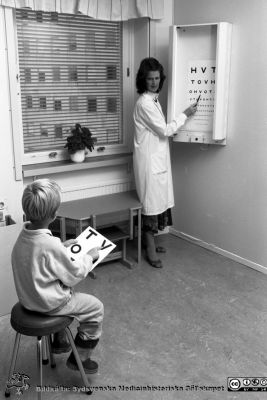 Ortoptisten Janet Hall Lindberg provar synskärpan på ett barn, 1987
Sjukhusfotograferna i Lund. Pärm Svart-vita neg. 1987. 130/-87. Provet görs med s.k. HVOT-tavla. Från negativ.
Nyckelord: Laboratorium;Lund;Universitetssjukhus;USiL;Ögon;Klinik;Oftalmiatrisk;Oftalmologisk;Barn