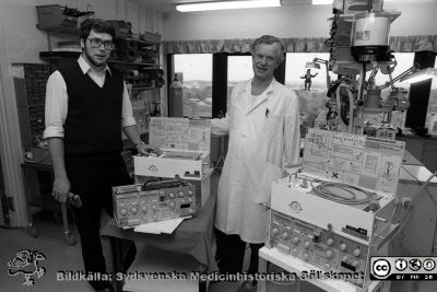 Professorn i medicinsk teknik Nils Gunnar Holmer och anestesiologen, docent Lars Nordström, med ett par ServoVentilatorer. 
Sjukhusfotograferna i Lund. Pärm Svart-vita neg. 1987. 146/87. Foto i januari 1988.
Nyckelord: Lasarettet;Lund;Universitetssjukhus;USiL;Anestesi;Medicinsk;Teknisk;Klinik;Avdelning;MTA;Ventilator;Respirator