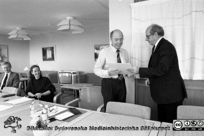 Diplom och medaljer delas ut för arbetarskydsarbete på Lasarettet i Lund 1988
Sjukhusfotograferna i Lund. Pärm Sv/v neg. 1988. 88-12-07.  Elektrikern Börje Lundberg mottar arbetarskyddsdiplom och medalj av direktionens ordförande Fredrik Swartling. Vid bordet från vänster sjukhusjurist Matts Wendel och ekonom Lillemor Gregorius som också skall få diplom och medalj. Från negativ.
Nyckelord: Lund;Lasarettet;Universitetssjukhus;USiL;Utmärkelse;Diplom;Arbetarskydd