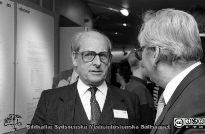 Fredrik Swartling på Forskningens Dag 1988
Sjukhusfotograferna i Lund. Pärm Sv/v neg. 1988.	75. II/88. Direktionsordföranden Fredrik Swartling på Forskningens Dag, i samspråk med professor Bengt Scherstén (?). Från negativ.
Nyckelord: Lasarettet;Lund;USiL;Universitetssjukhus;Forskningens;Dag;Symposium;Utställning