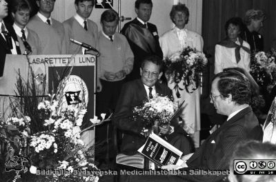 Fernströmspristagare på Forskningens Dag 1988 i Lund
Sjukhusfotograferna i Lund. Pärm Sv/v neg. 1988  75. IV/88. Fernströmssymposium "Att sova och att drömma" på Forskningens Dag. På främsta raden i auditoriet H.M. kung Carl XVI Gustaf och HM drottning Silvia (skymd).
Årets mottagare av Fernströms Nordiska Pris, Peter Perlmann, i stolen framför kungligheterna. Prismotivering: ”För hans metodologiskt och grundvetenskapligt framstående insatser inom immunologin av stor betydelse för medicinsk forskning och utveckling”.
I bakgrunden studentsångare, en marskalk (Leif Salford) och Ingegärd Lindqvist (kanslidirektör och ansvarig för arrangemangen) och en av mötesvärdinnorna, Gunilla Sernelin. Från negativ.
Nyckelord: Lasarettet;Lund;USiL;Universitetssjukhus;Forskningens;Dag;Symposium;Prisutdelning