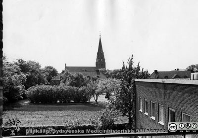 Utsikt mot Allhelgonakyrkan från norr på 1950-talet
Bilder från sjukhusprästen Bernt Eriksson, 1960 - 2000-talen. Foto från den på 1950-talet byggda barnkliniken. Taken på dåvarande infektionskliniken skymtar hitom kyrkan. Foto Troligen något av 1950-talets sista år, innan infektionsklinikens paviljonger revs c:a 1962. Från foto. 
