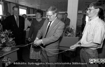 Invigning på telefonväxeln efter modernisering av utrustningen
Lasarettsfotograferna i Lund,  pärm S/V Neg. 1995. 54. Sjukvårdsdirektören Leif Granath klipper ett par telefonsladdar som ersätter det klassiska bandet, alltmedan direktionsmedlemmen Britt-Marie Lundqvist glatt ser på. Mannen till höger i bild är teknikern Jörgen från Televerket och växelns allt-i-allo när det gällde teleteknik. Han till vänster lär ha varit en ansvarig administratör från Televerket. Från negativ
Nyckelord: Lasarettet;Lund;Universitetssjukhuset;USiL;Telefonväxel;Invigning