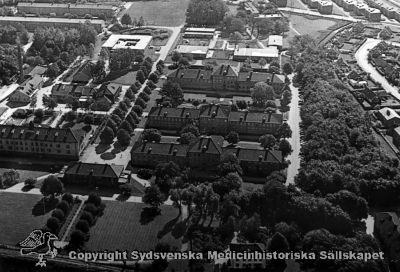 Flygfoto över Vipholms sjukhus från väster
Vipeholm exteriört. Flygfoto över sjukhusområdet. 
- Villaområdet söder om sjukhuset (till höger i bilden) är tämligen väl utbyggt, och de ljusa byggnaderna i fotots övre del (områdets östra del) byggdes i mitten på 1960-talet. Fotot är rimligen taget tidigast i mitten på 1960-talet och kanske i samband med att utbyggnaden österut stod klar. Omonterat
Nyckelord: Omonterat;Kapsel 15;Exteriört;Vipeholm;Flygfoto