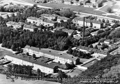 Flygfoto över Vipeholms sjukhus på 1960-talet, från öster
Text på bilden: "5166-8 Foto: SKANDINAVISK AEROTJÄNST. Granskad och godkänd av Försvarsstaben." Foto från öster. 
Publicerad på sid 12 i Carlén-Nilsson C, Holmér U (1998) Röster från Vipeholm. Stiftelsen medicinhistoriska museerna i Lund och Helsingborg, Lund, pp. 1-127. Bildtext där: "Flygbild från 1960-talet över sjukhusområdet". Vykort
Nyckelord: Vipeholm;Flygfoto;1960-talet;Exteriört;Kapsel 15;Foto;Omonterat