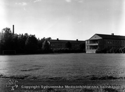 Idrottsplatsen på Vipeholms sjukhus, med kvinnliga paviljonger i bakgrunden
Vipeholm exteriört. Idrottsplanen och kvinnliga paviljonger. Den bortre byggdes 1937, den hitre 1950. Foto under 1900-talets andra halva. Omonterat
Nyckelord: Omonterat;Foto;Kapsel 15;Vipeholm;Idrottsplats;Kvinnlig;Paviljong;Exteriört;Fotbollsplan