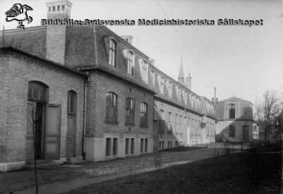 Ekonomibyggnaden från 1904: Tvätt. Foto: Lina Jonns eftr (Per Bagge) 1906
Lasarettet i Lund, södra området: exteriör. Allhelgonakyrkans spira sticker upp i bakgrunden.
Notera linbanekorgen vid tornet i husets bortre ända. 
Nyckelord: Lasarettet;Lund;Södra; Området;Exteriör;Tvätt;Ekonomi;