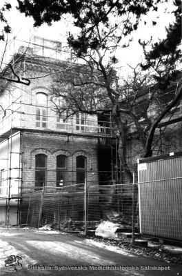 Gamla kirurgiska klinikens annex renoveras (5), rimligen på 1980-talet
Nr 5 i en serie bilder tagna runt fasaden vid dess renovering, i motsols ordning runt huset och rimligen på 1970-talet. Fotograf okänd.
Nyckelord: Kapsel 01;Regionarkivet;Lund;Lasarettet;Universitetssjukhuset;Söder;Kirurgiska;Kliniken;Gamla;Annex;Renovering;1970-talet
